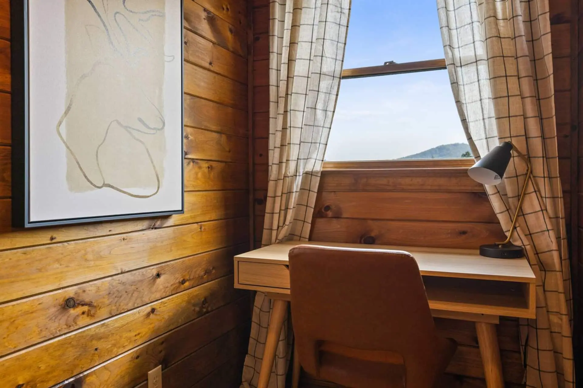 A cozy workspace tucked beside the window offers peaceful views and natural light—perfect for remote work, journaling, or planning the day’s adventures while enjoying the relaxing cabin atmosphere.