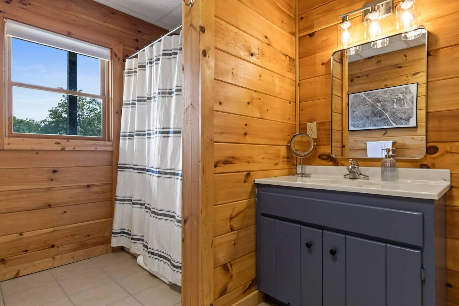 Bright and clean full bathroom featuring a shower/tub combination, fresh towels, and warm cabin-style wood accents.
