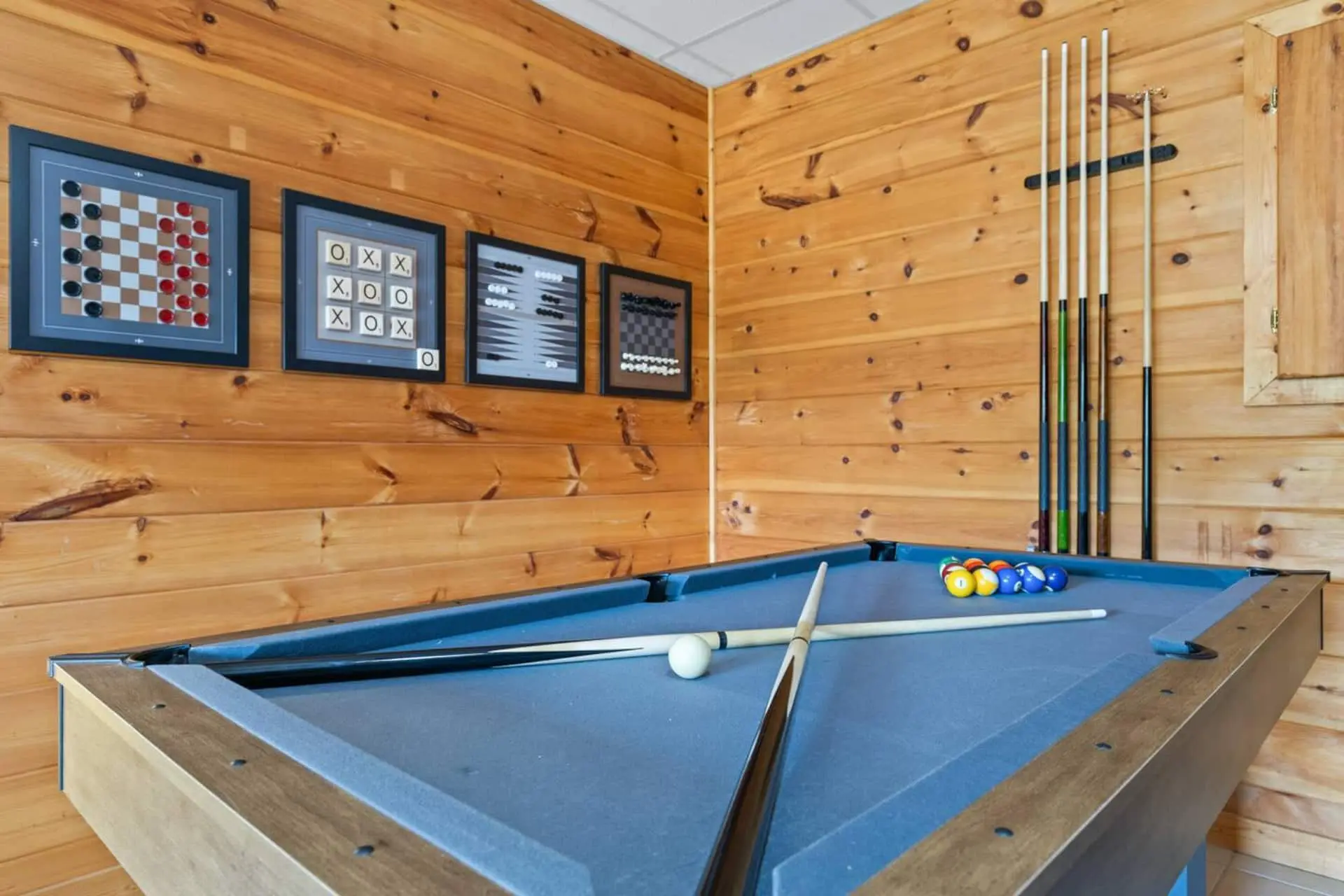 Game on! This cozy wood-paneled game room features a kid-friendly size pool table, cue rack, and classic wall games—perfect for friendly competition and laid-back evenings. A great spot to unwind, laugh, and make memories indoors.