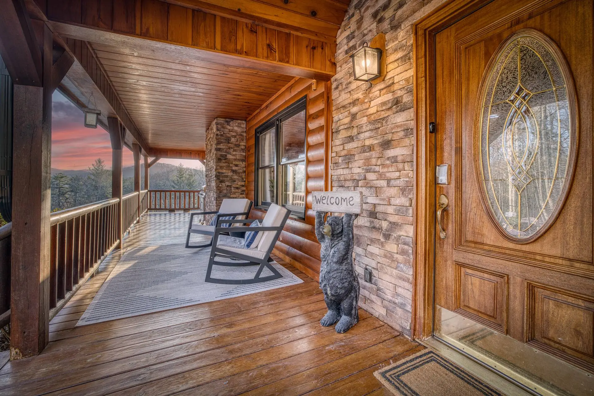 Welcoming cabin porch with rockers, rug, and sunset mountain views