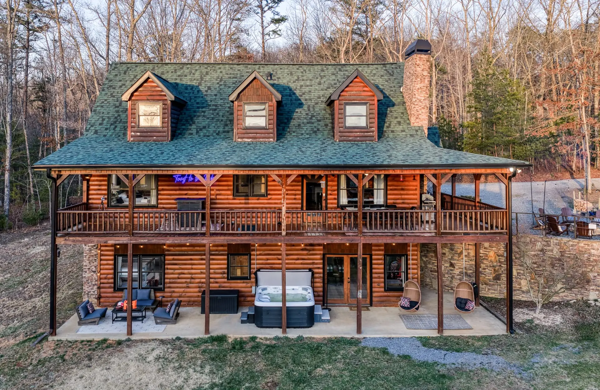 Spacious log cabin with decks, hot tub, and fire pit in the woods.