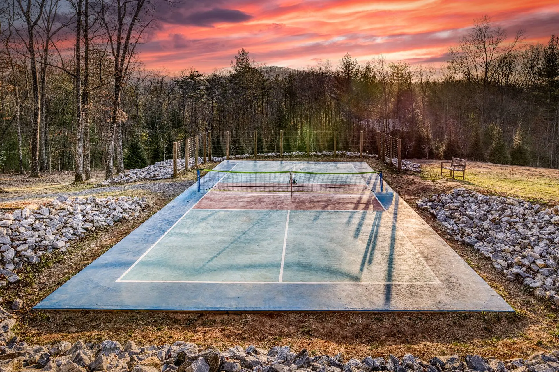 Private pickleball court at dusk—enjoy a friendly match surrounded by peaceful woods and a colorful sunset sky. This full court is exclusively for guests, offering a fun and relaxing way to unwind after a day of exploring.